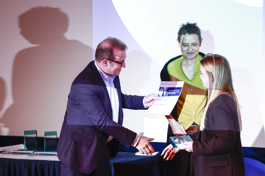 Man handing out a certificate to a young woman on a stage