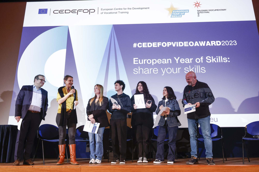 4 women and 3 men on a stage, CedefopVideoAward visual at the background