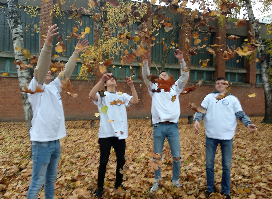 Young students with white t-shirts throwing leaves