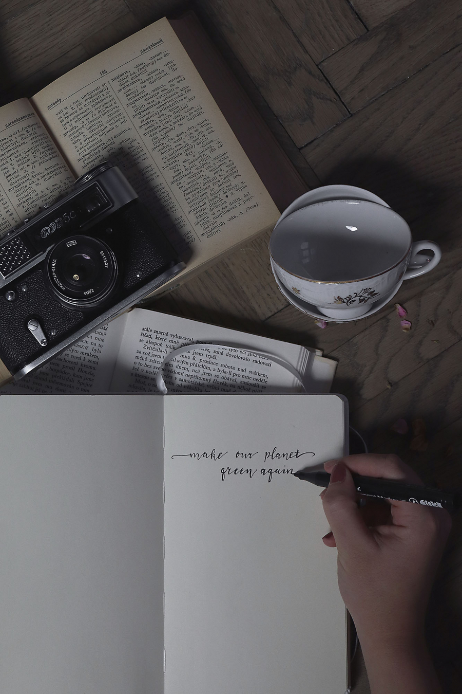 Books, photo camera, coffee cup, hand writing on a notebook