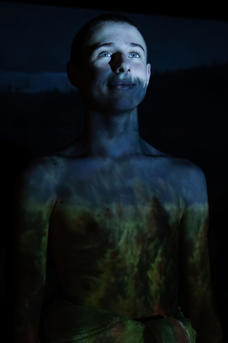 Young boy with photos of forests and nature projected on his body - the boy looks happy