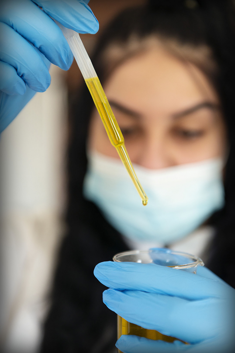 Young woman uses pipette for filling test tube with liquid